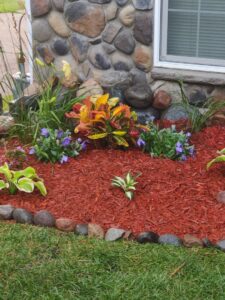 A vibrant landscaped garden bed with red mulch and various plants, maintained by K&R Lawn Care in Pass Christian, MS.