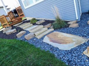 A beautifully landscaped area with large stepping stones and gravel by ALL Lawn Care Service in Saint Louis, MO