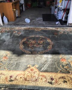 A large area rug being cleaned outdoors, showing a clear before and after section by Ecodry Carpet Cleaning Las Vegas, NV.