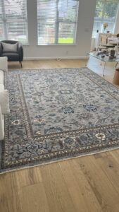 A large, intricately patterned area rug professionally placed on a wooden floor by Kaskas Rug Gallery in Austin, TX.