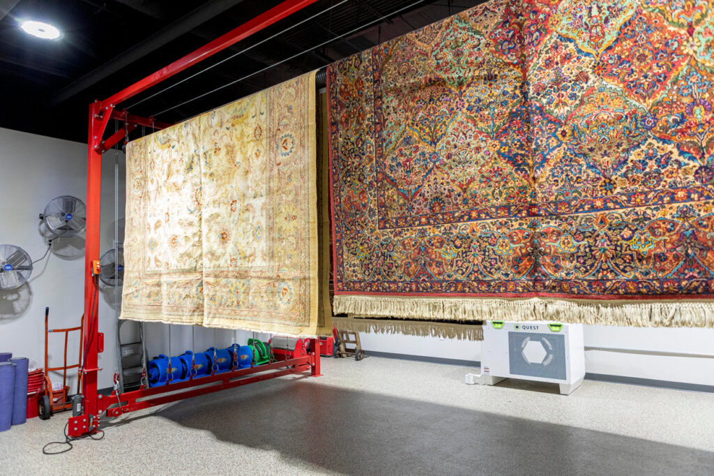 Large area rugs hanging on specialized drying equipment after cleaning at Mussallem Area Rug Specialist in Jacksonville, FL.