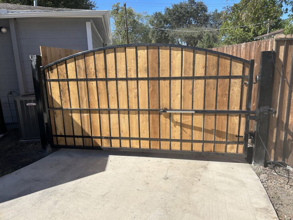 A large automatic gate featuring wood panels within a sturdy metal frame by Craftsman Automatic Gates in Dallas, TX