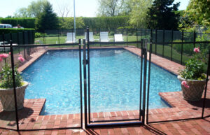 A spacious backyard featuring a pool enclosed by a black mesh safety fence, installed by Pool Guard in North Charleston, SC.