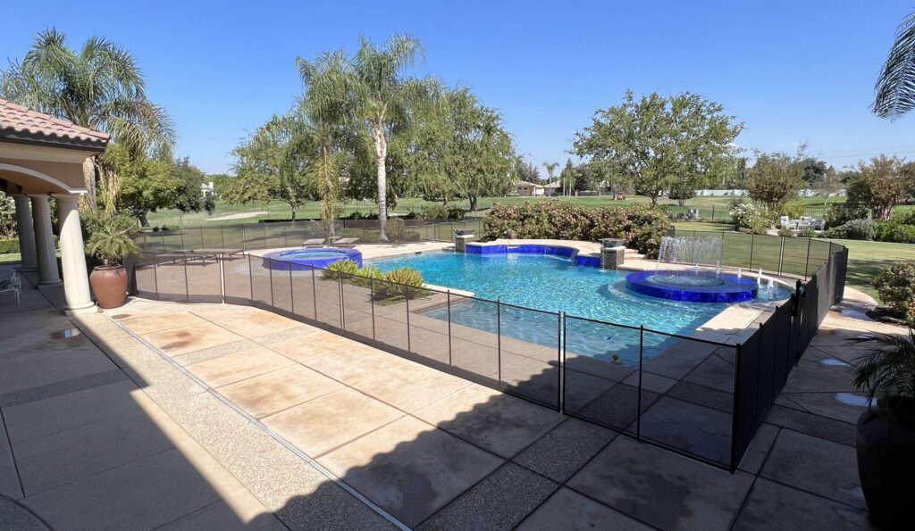 A comprehensive black mesh pool fence installation for a large backyard swimming pool overlooking a golf course by A Safe Pool Enclosures in Bakersfield, CA.