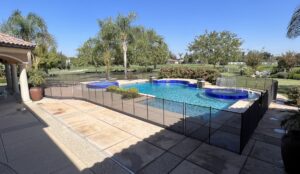 A comprehensive black mesh pool fence installation for a large backyard swimming pool overlooking a golf course by A Safe Pool Enclosures in Bakersfield, CA.