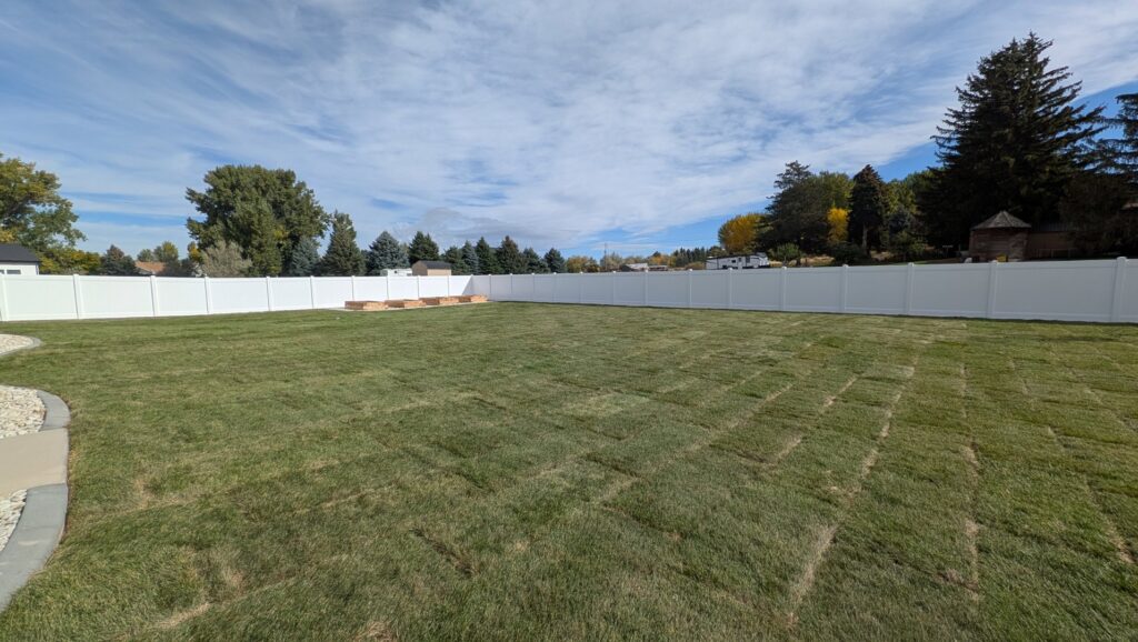 A large backyard enclosed by a white vinyl privacy fence installed by 208 Fence and Gate in Idaho Falls, ID.