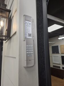 A large black full-view glass garage door installed on a white brick commercial building by Signature Garage Doors in Huntsville, AL.