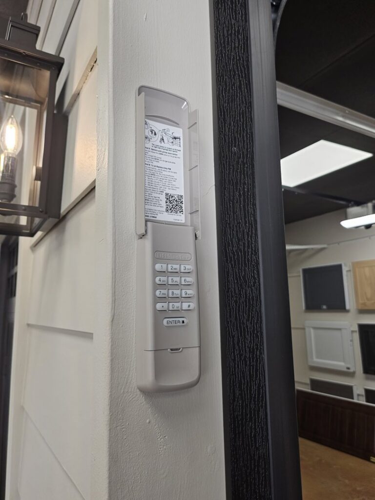 A large black full-view glass garage door installed on a white brick commercial building by Signature Garage Doors in Huntsville, AL.