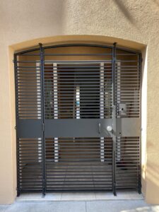 A large black metal security gate with horizontal bars installed in an arched entryway by Fierro Iron Works Inc. in San Francisco, CA.