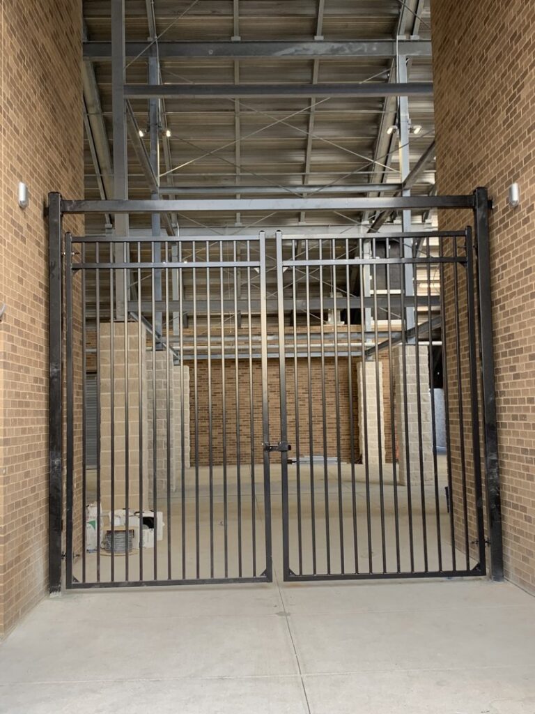 A large black metal double gate installed for a commercial or public entrance by G L Fence & Remodeling in Arlington, TX.
