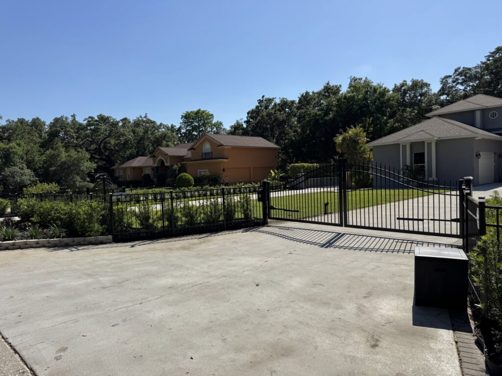 A large black metal double driveway gate and fence installed by Elite Fence and Outdoor of Tampa Bay in Tampa, FL.