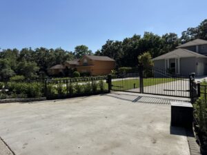 A large black metal double driveway gate and fence installed by Elite Fence and Outdoor of Tampa Bay in Tampa, FL.
