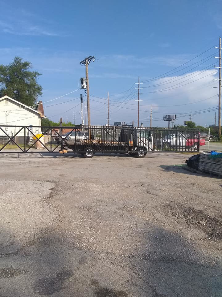A large black metal fence or gate section being transported on a truck by Kennedy Fence Corporation in St. Louis, MO.