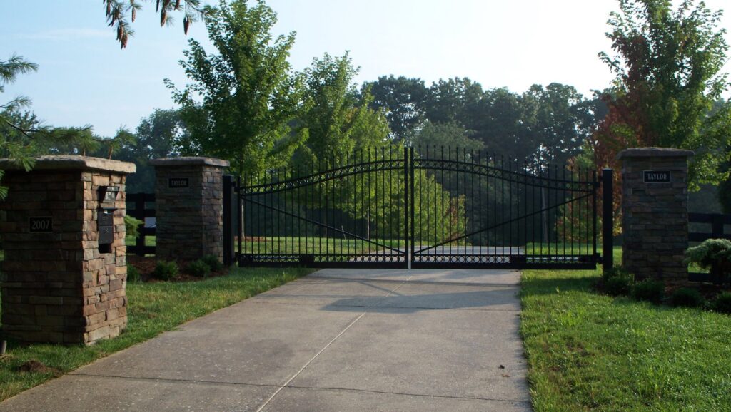 A large black ornamental entry gate with stone pillars installed by Raatz Fence Company in Louisville, KY.