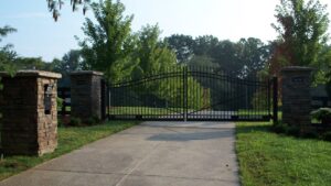 A large black ornamental entry gate with stone pillars installed by Raatz Fence Company in Louisville, KY.
