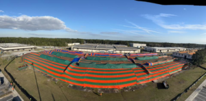 A large commercial building covered in a red and green fumigation tent by Rivers Pest Control Service, Inc. in Jacksonville, FL