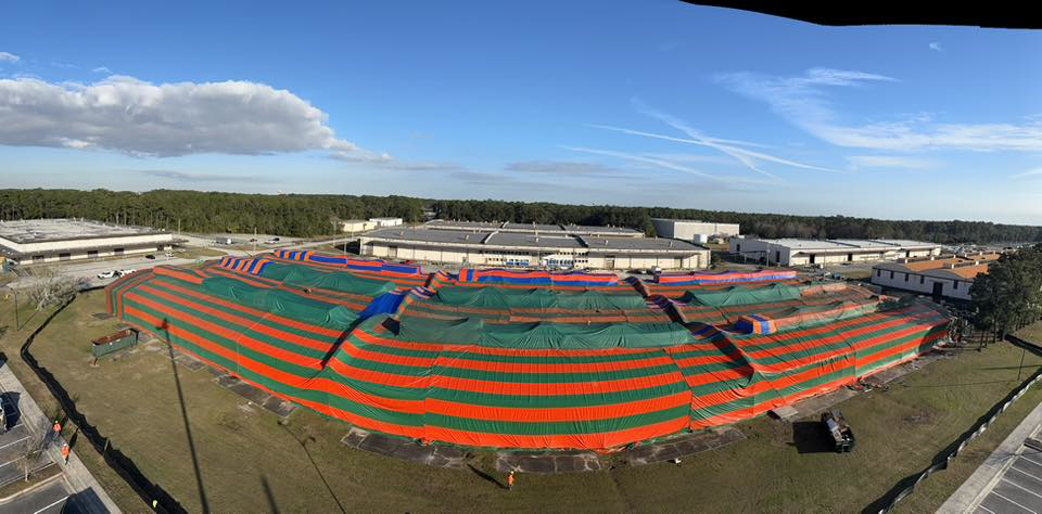 A large commercial building covered in a red and green fumigation tent by Rivers Pest Control Service, Inc. in Jacksonville, FL