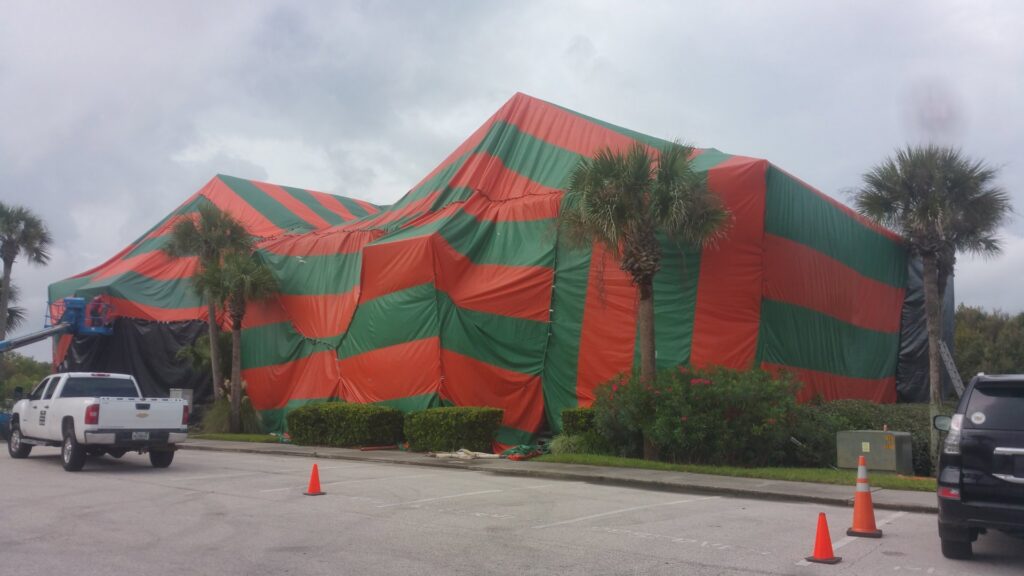 A large building covered in a red and green fumigation tent with a Rivers Pest Control Service, Inc. truck in the foreground in Jacksonville, FL