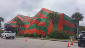 A large building covered in a red and green fumigation tent with a Rivers Pest Control Service, Inc. truck in the foreground in Jacksonville, FL