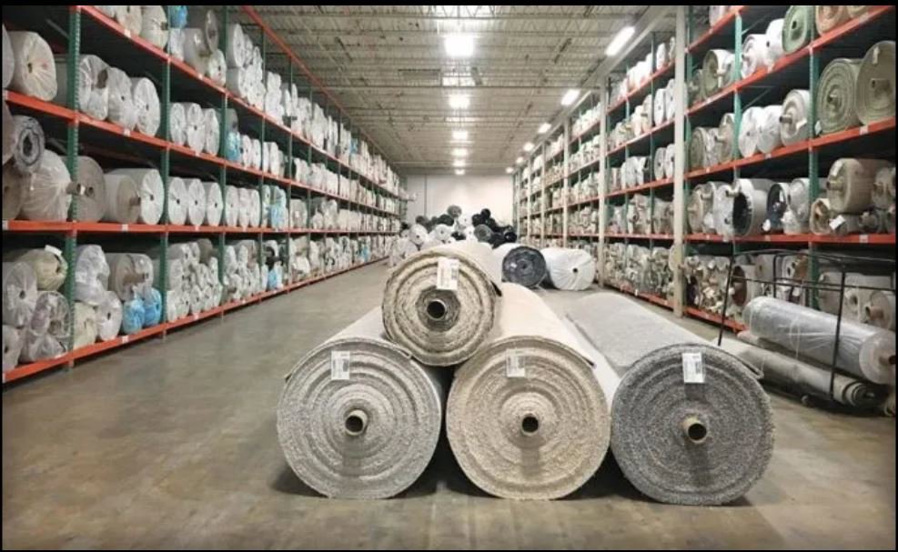 A vast warehouse filled with numerous rolls of carpet on shelves, indicating extensive inventory at AFAB Carpets in Tampa, FL.