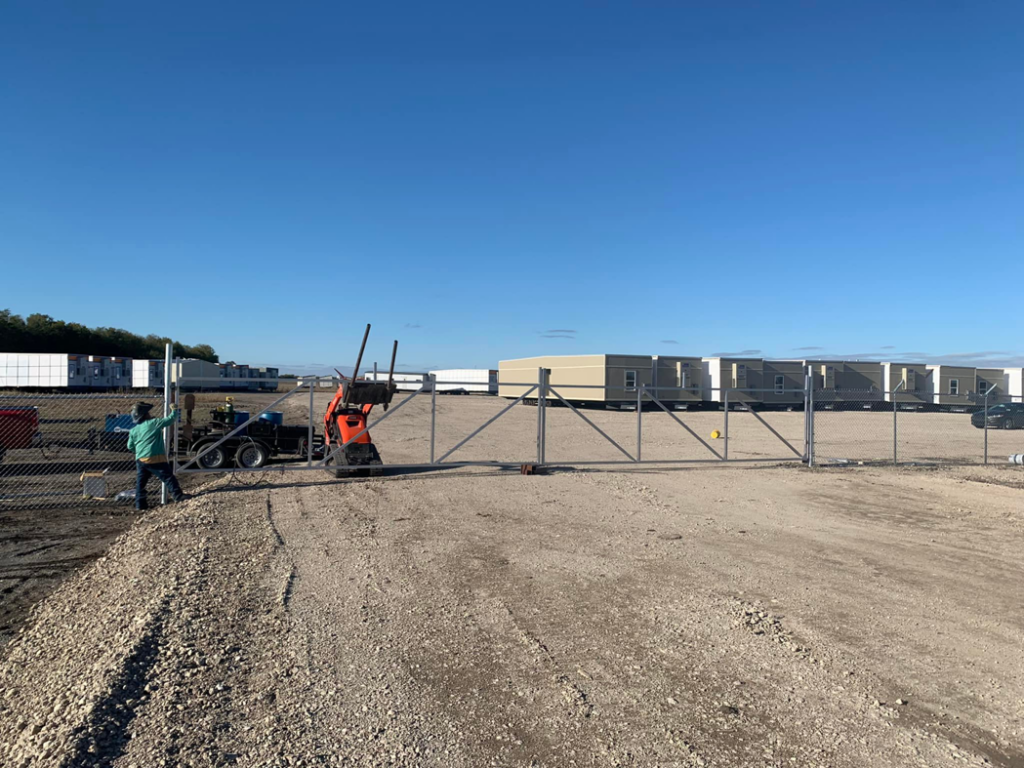 Workers installing a large chain-link sliding gate in a commercial or industrial area by BAR Z Fencing and Welding LLC in Midlothian, TX