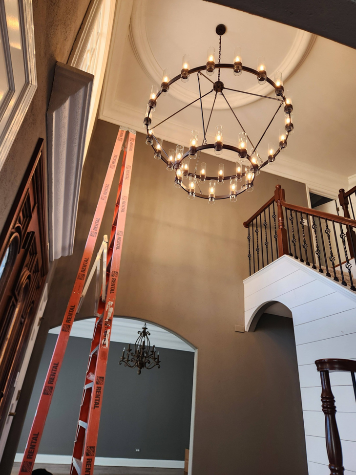 A large circular chandelier installed in a high-ceiling entryway by Ed's Electrical & Mounting services in Chicago, IL.
