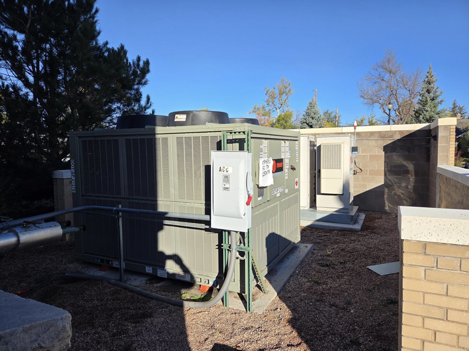 A large outdoor commercial HVAC unit with electrical connections and piping installed by High Standard HVAC LLC in Cheyenne, WY.
