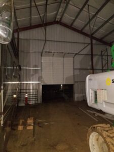 A large commercial overhead door, partially open, inside a warehouse building, installed by Xpress Doors LLC in Salem, OR