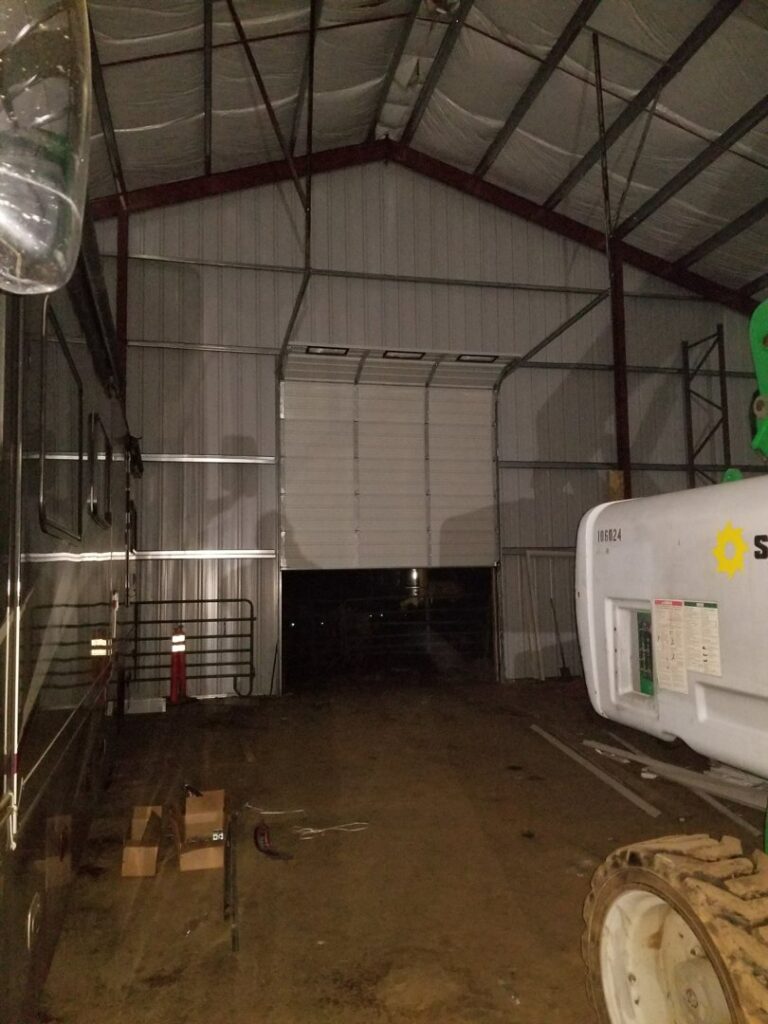 A large commercial overhead door, partially open, inside a warehouse building, installed by Xpress Doors LLC in Salem, OR