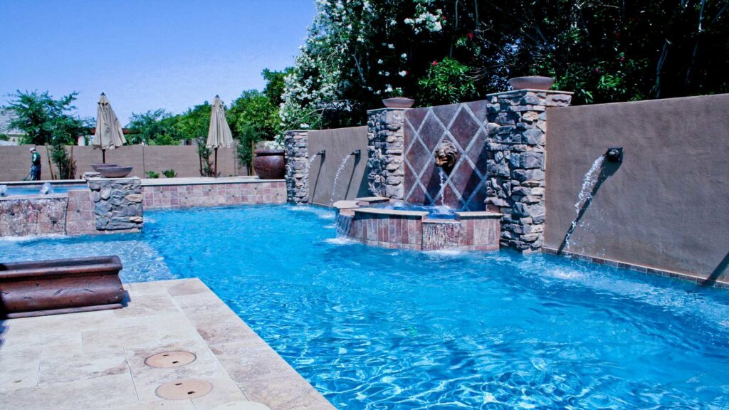 A large custom swimming pool with multiple water features and stone accents by Blue Magic Pools and More Inc. in Gilbert, AZ.