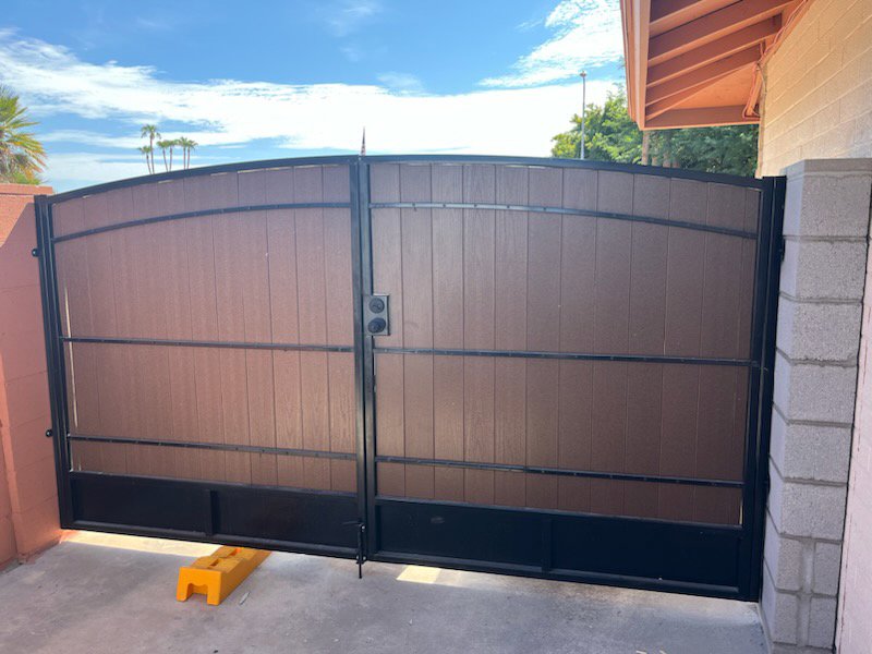 A large double driveway gate with wood-look panels and metal frame installed by Arce Masonry LLC in Glendale, AZ