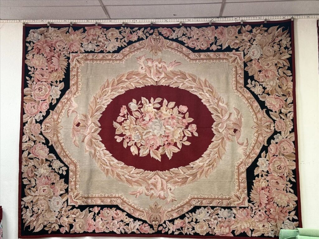 A large wall rug featuring an elaborate floral design, available at Woven Treasures, Inc in Mobile, AL.