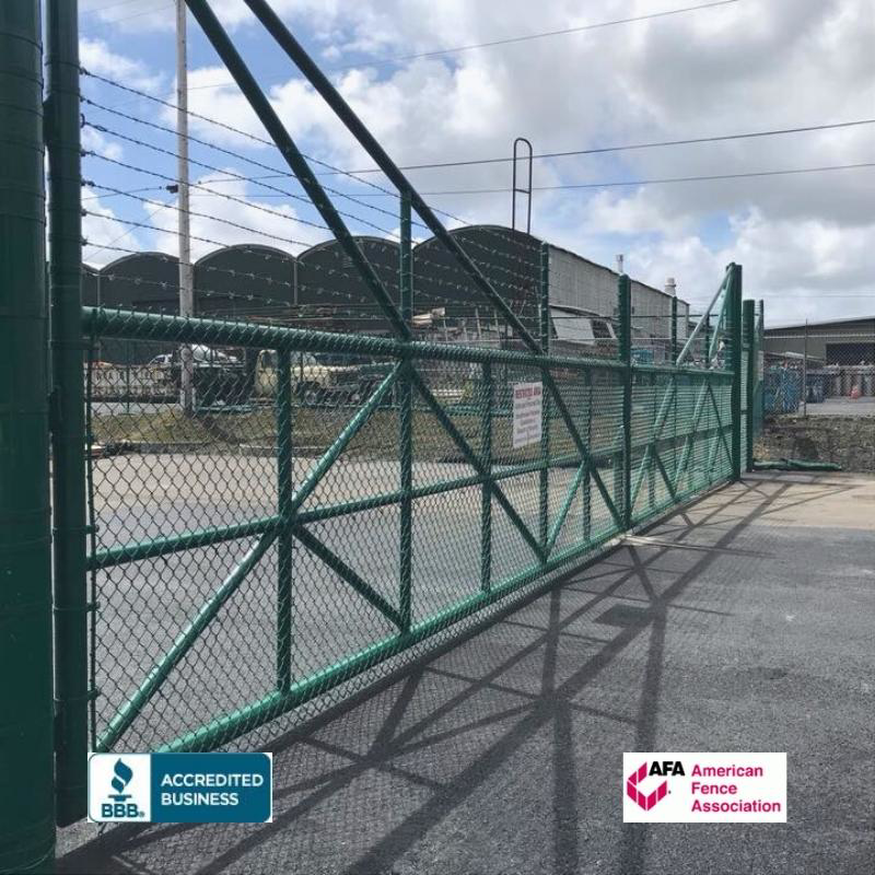 A large green chain-link gate with barbed wire, installed by David's Fencing Inc. in Waipahu, HI.