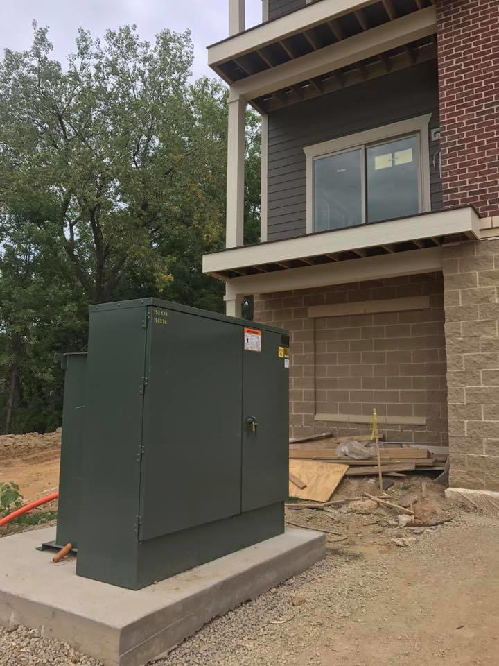 A large green electrical transformer box installed on a concrete pad next to a building by Kadlec Electric Inc. in Elgin, IL.
