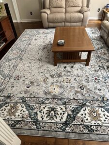 A spacious grey area rug with floral and medallion patterns in a living room, a service from Yas Rugs in Lexington, KY.