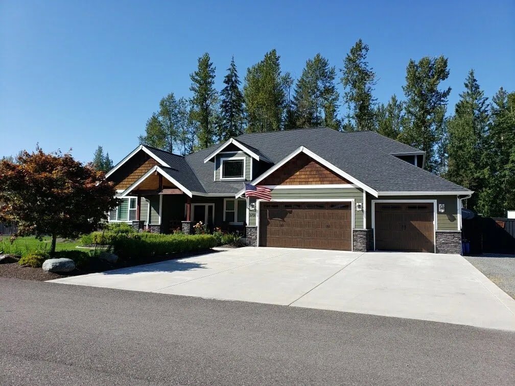 A large residential house featuring two brown garage doors installed by Overhead Door Company of Everett, Inc in Everett, WA.