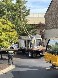Workers overseeing the installation of a large commercial HVAC unit with a crane for Nortek Environmental, Inc. in Naperville, IL.