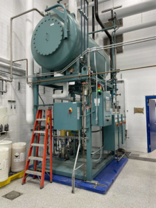 A large industrial boiler unit with complex piping and controls, part of an installation by Dean Boiler, Inc in Grand Rapids, MI.