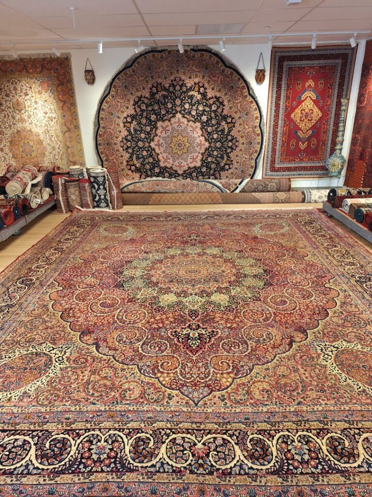 A large, intricately patterned Persian rug laid out on the floor at Art Of Persia in Portland, OR.