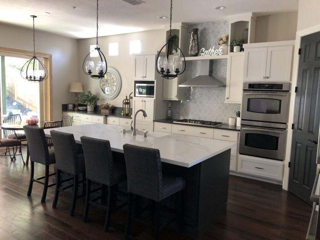 Spacious kitchen with a dark island, white cabinets, and dark wood flooring by Sulcas Carpets & more in Elk Grove, CA