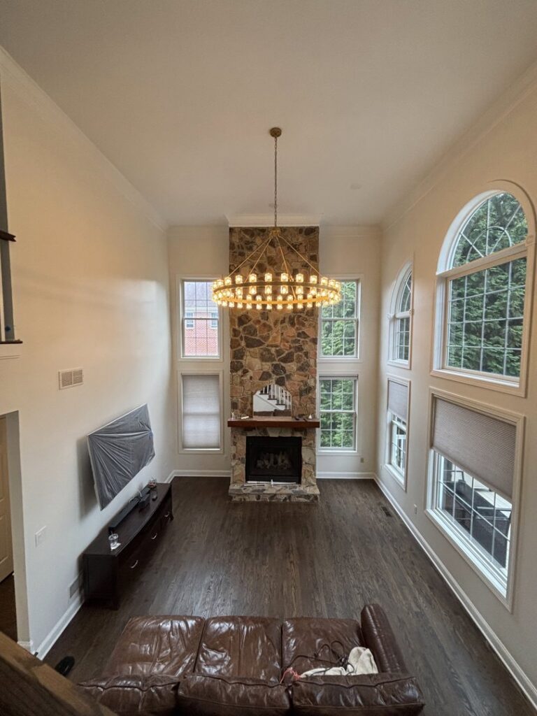 A grand chandelier installed in a spacious living room with high ceilings by Abe Electric LLC in Wallingford, CT.