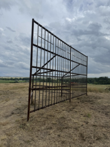 A large, robust metal fence structure standing in a field, built by Deer Creek Ag Services in Ranchester, WY.