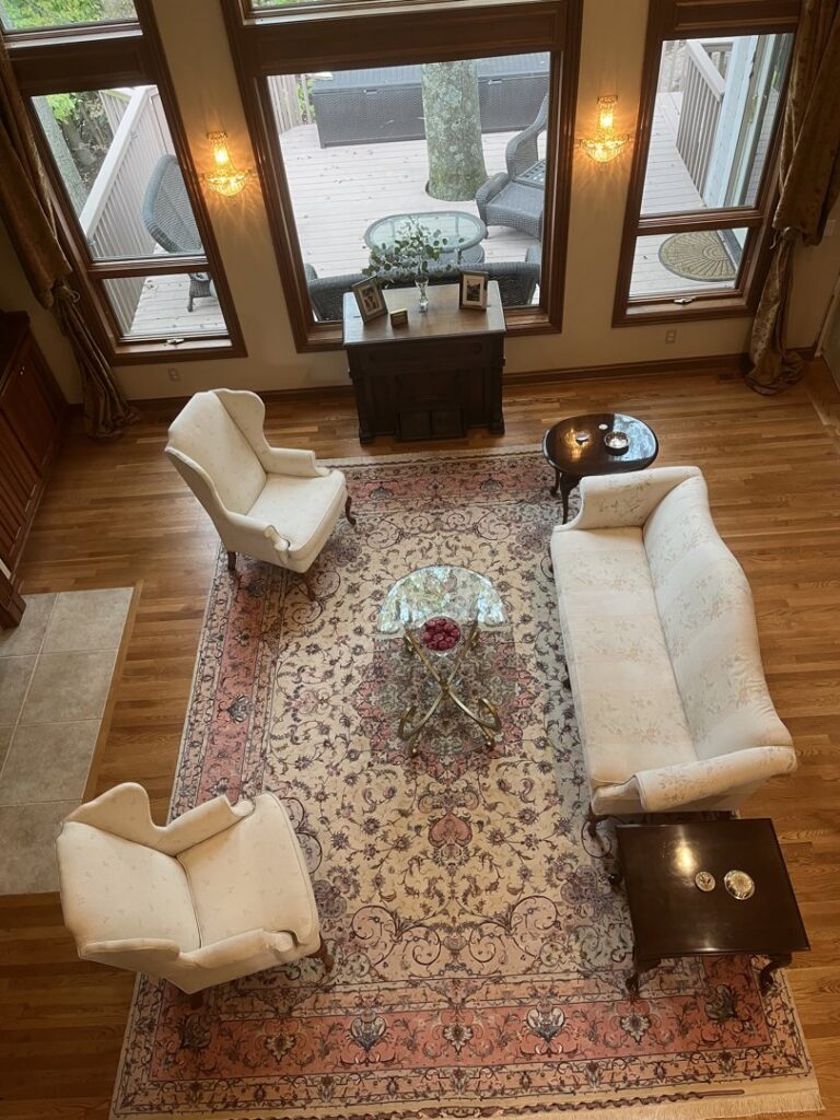 An aerial view of a large, light-colored oriental rug defining a living room space, expertly placed by Borokhim's Oriental Rugs in Madison, WI.