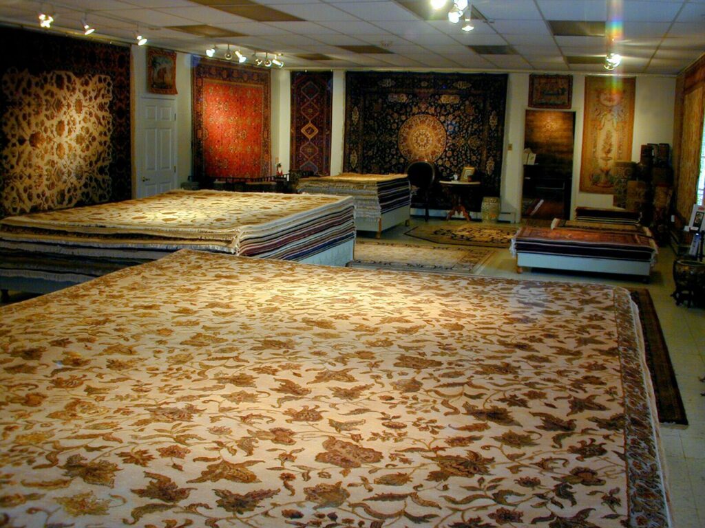 A spacious showroom displaying a wide variety of oriental rugs laid out on the floor and stacked at Brandon Oriental Rugs, Furlong, PA.