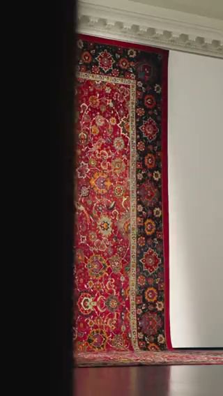 A large, ornate red oriental rug displayed, partially rolled out, at Accents Galleria in Kansas City, MO
