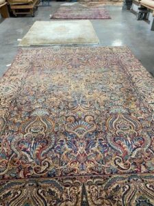Several large ornate rugs laid out on a concrete floor, likely at J L Williard Carpet Care in High Point, NC.