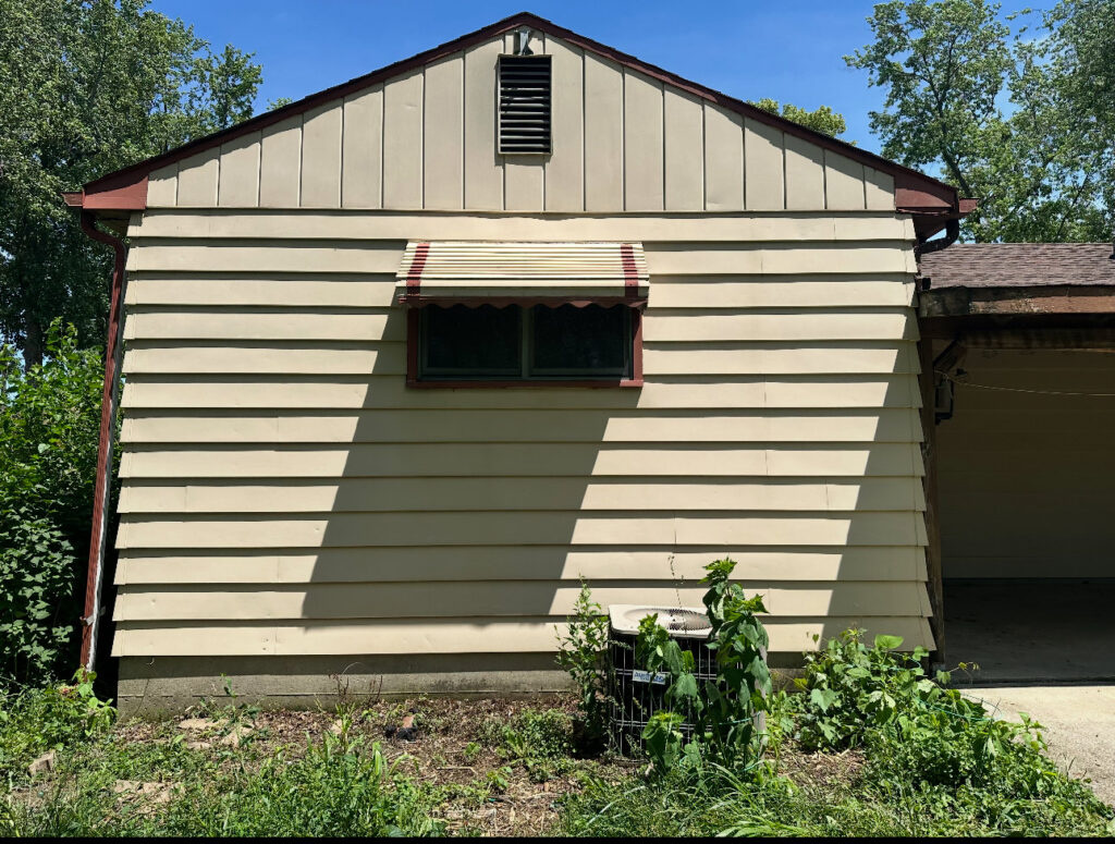 A large, overgrown bush next to the side of a house, indicating trimming services by Geno's Father & Son Lawn Services Llc in Hammond, IN