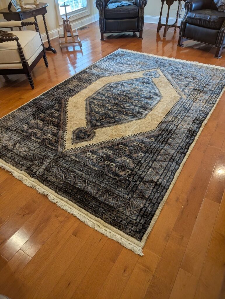 A large, patterned area rug in blue and cream tones on a hardwood floor, installed by Yas Rugs in Lexington, KY.