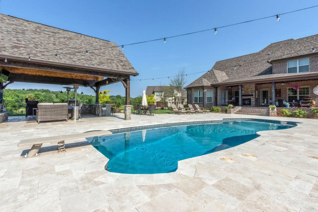 A large swimming pool with a diving board and an expansive outdoor kitchen area by Top Tier Pools in Franklin, TN.