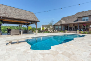 A large swimming pool with a diving board and an expansive outdoor kitchen area by Top Tier Pools in Franklin, TN.